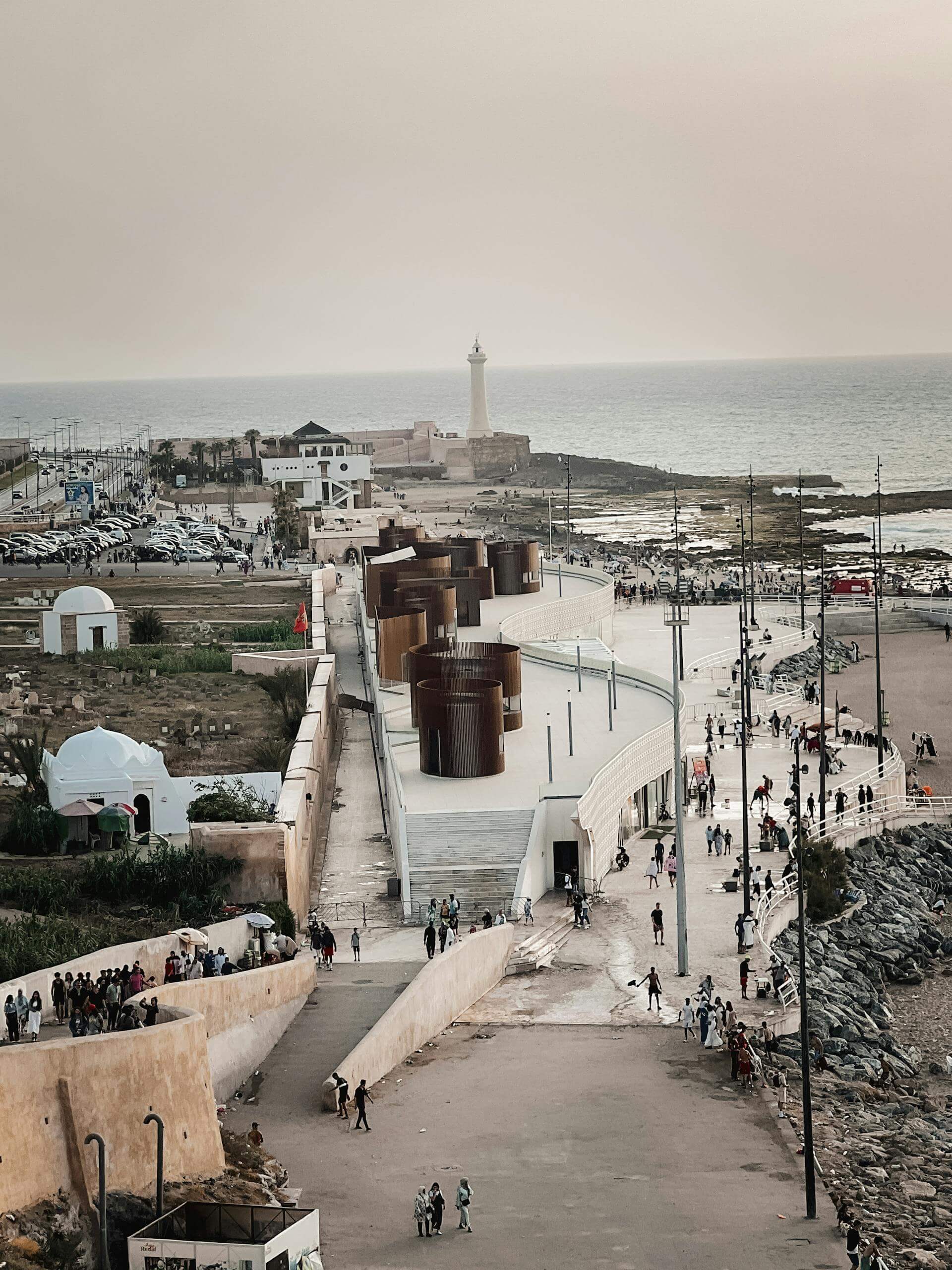 Aerial view of Rabat's coastline featuring a lighthouse and bustling walkway.